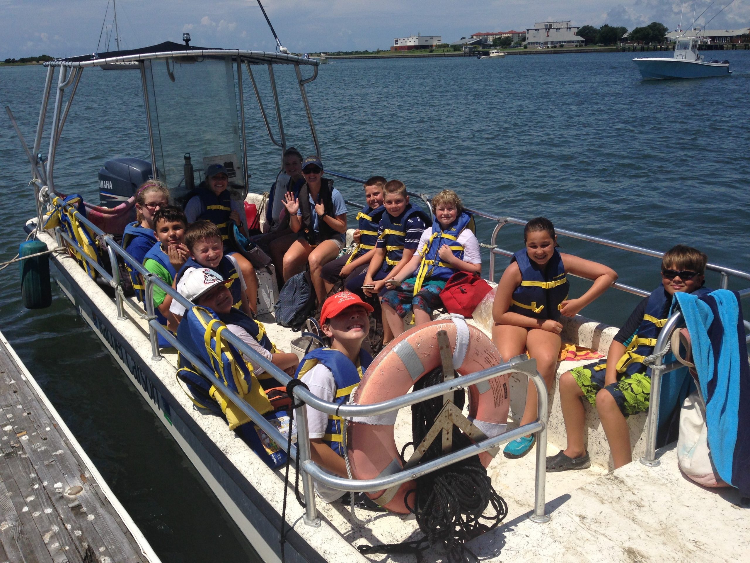 a pontoon boat with more than a dozen children aboard moored at a dock
