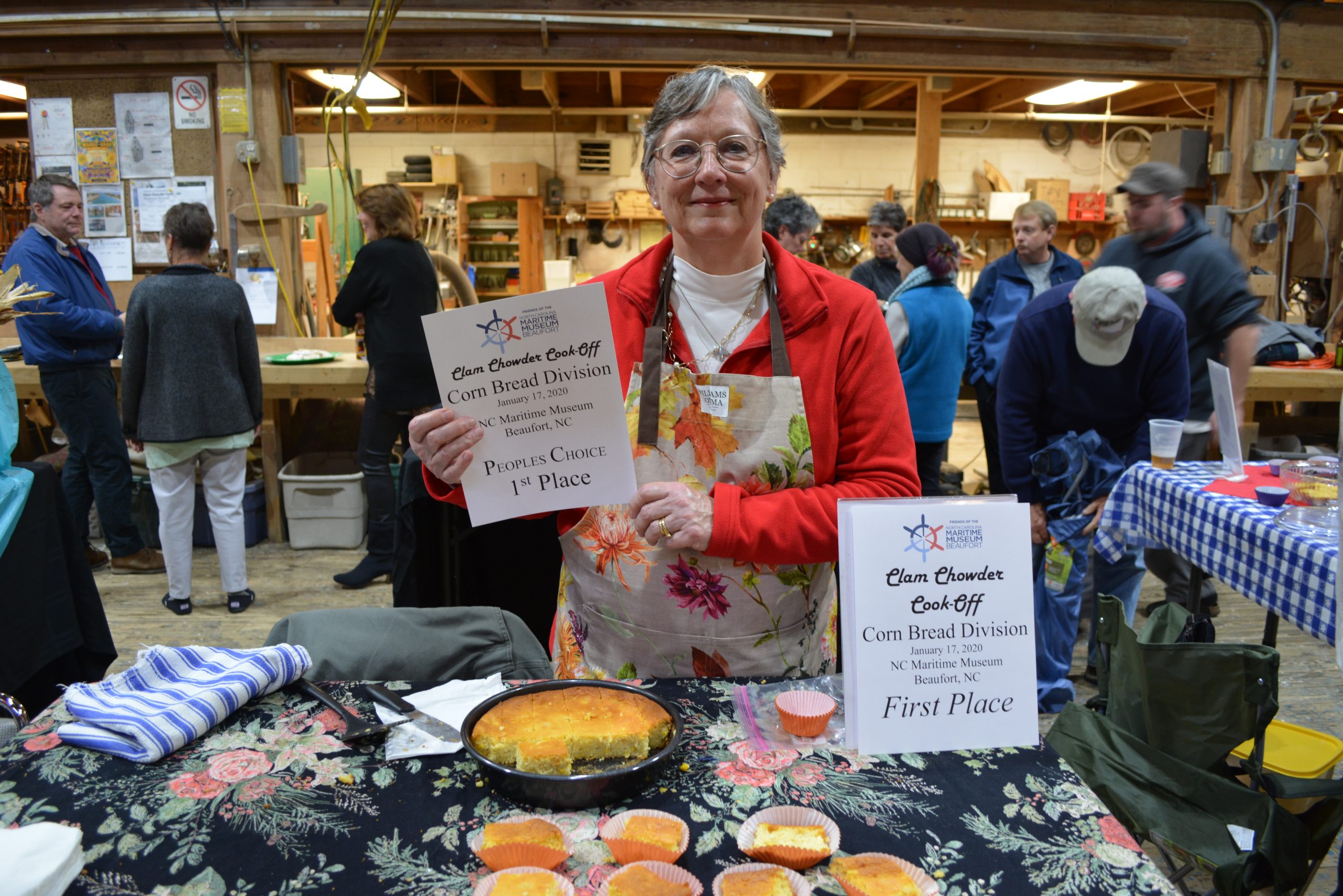 Woman holding printed sign declaring her cornbread the winner at the crab cake cookoff