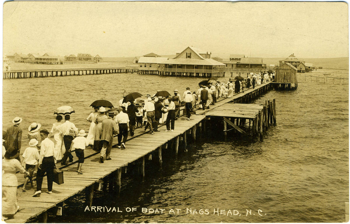 historic photo showing crowds of people walking on dock over water