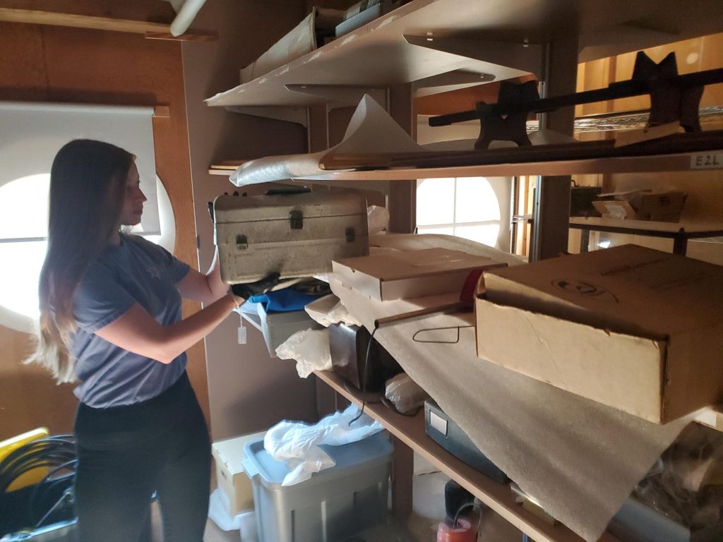 woman pulling old toolbox off shelf