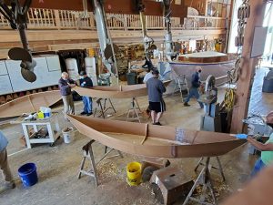 group of people around unfinished boat hulls